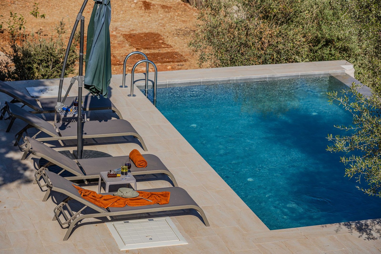 Serene hotel poolside setting with sun loungers and umbrellas beside the water