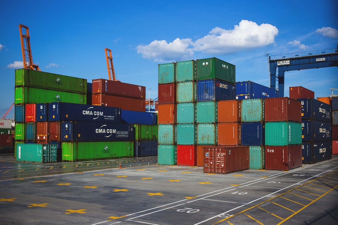 Patio de contenedores en un puerto con grúas y contenedores apilados, importación de mobiliario de exterior desde China