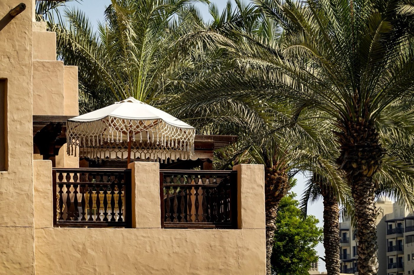 Terraza de hotel con sombrilla de tela blanca, mobiliario de exterior y palmeras, sombrillas de jardín para hostelería fabricadas en China
